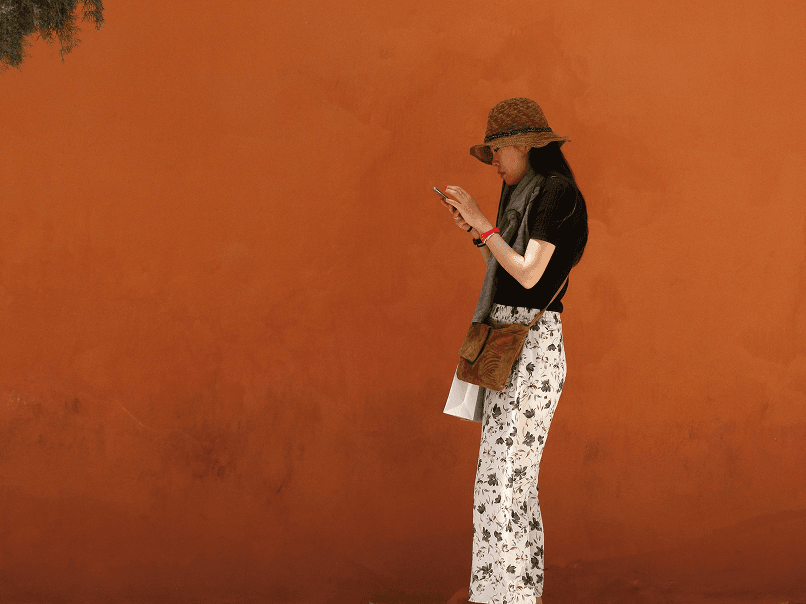 Woman looking at phone in front of orange wall