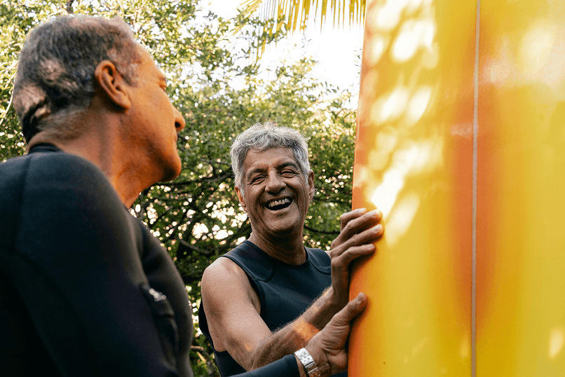 Retired man with surfboard laughing